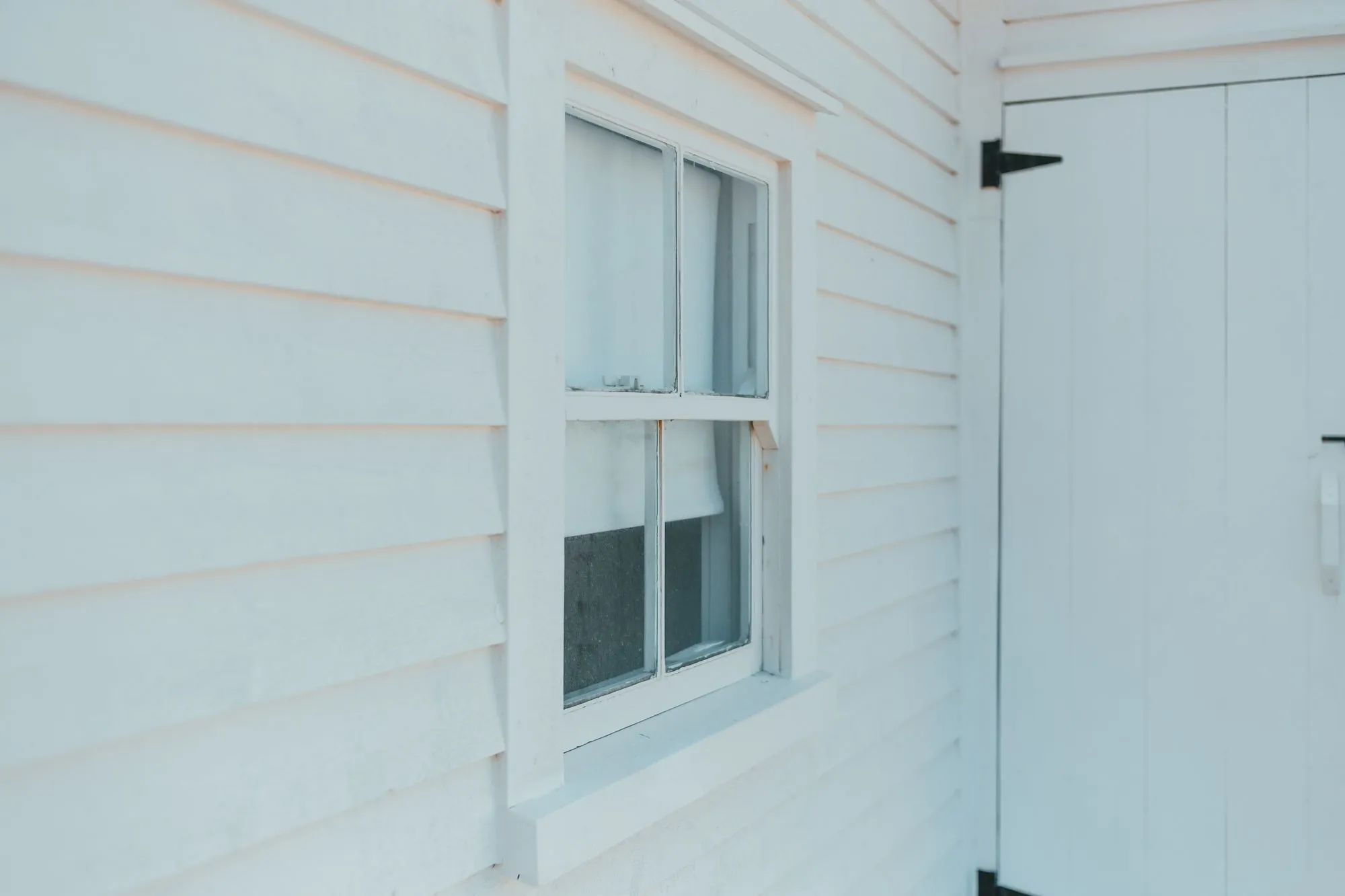 White clapboard siding running past a window on the side of a house