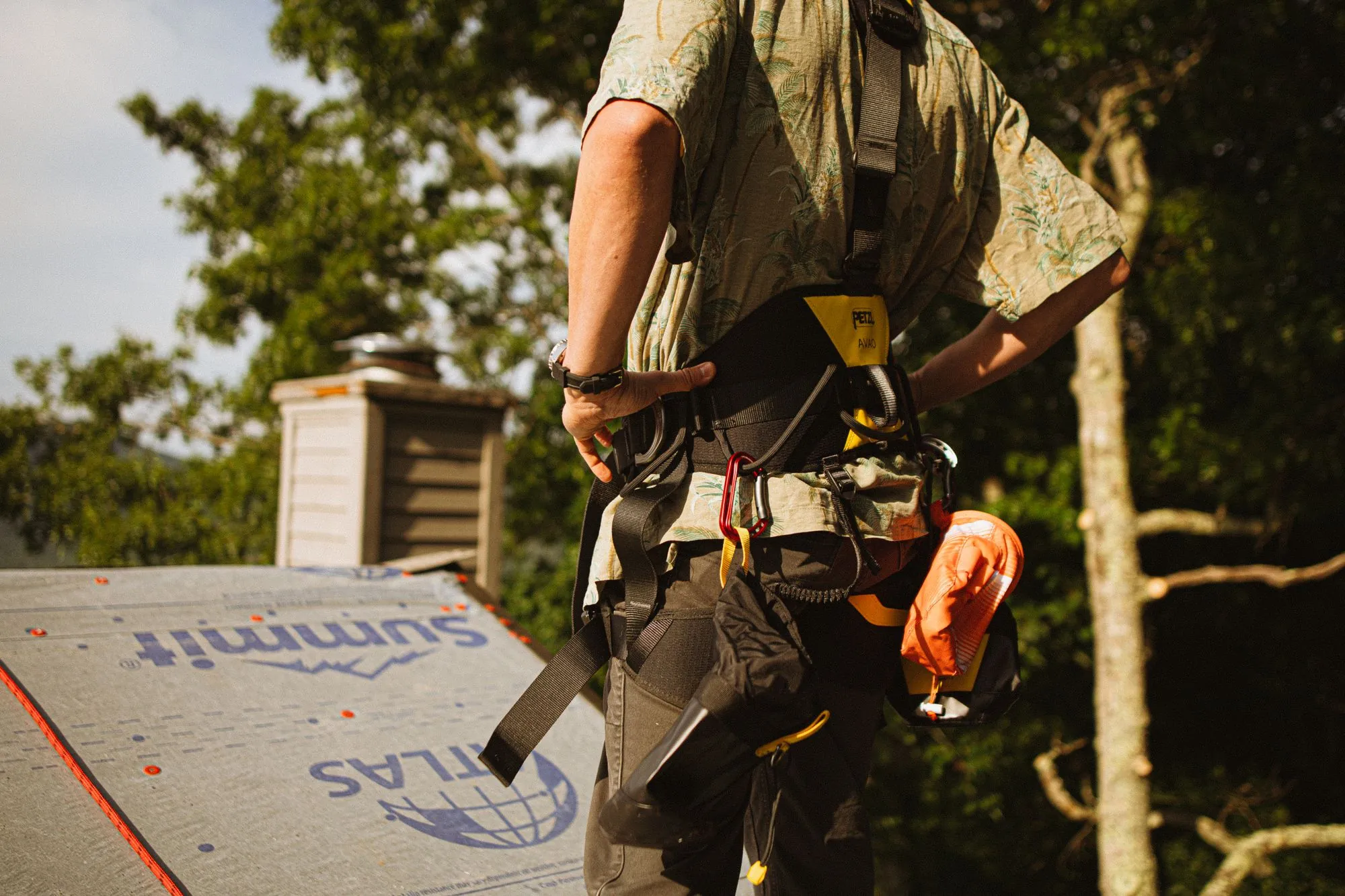 A roofer in a safety harness working across a deck laid with underlayment