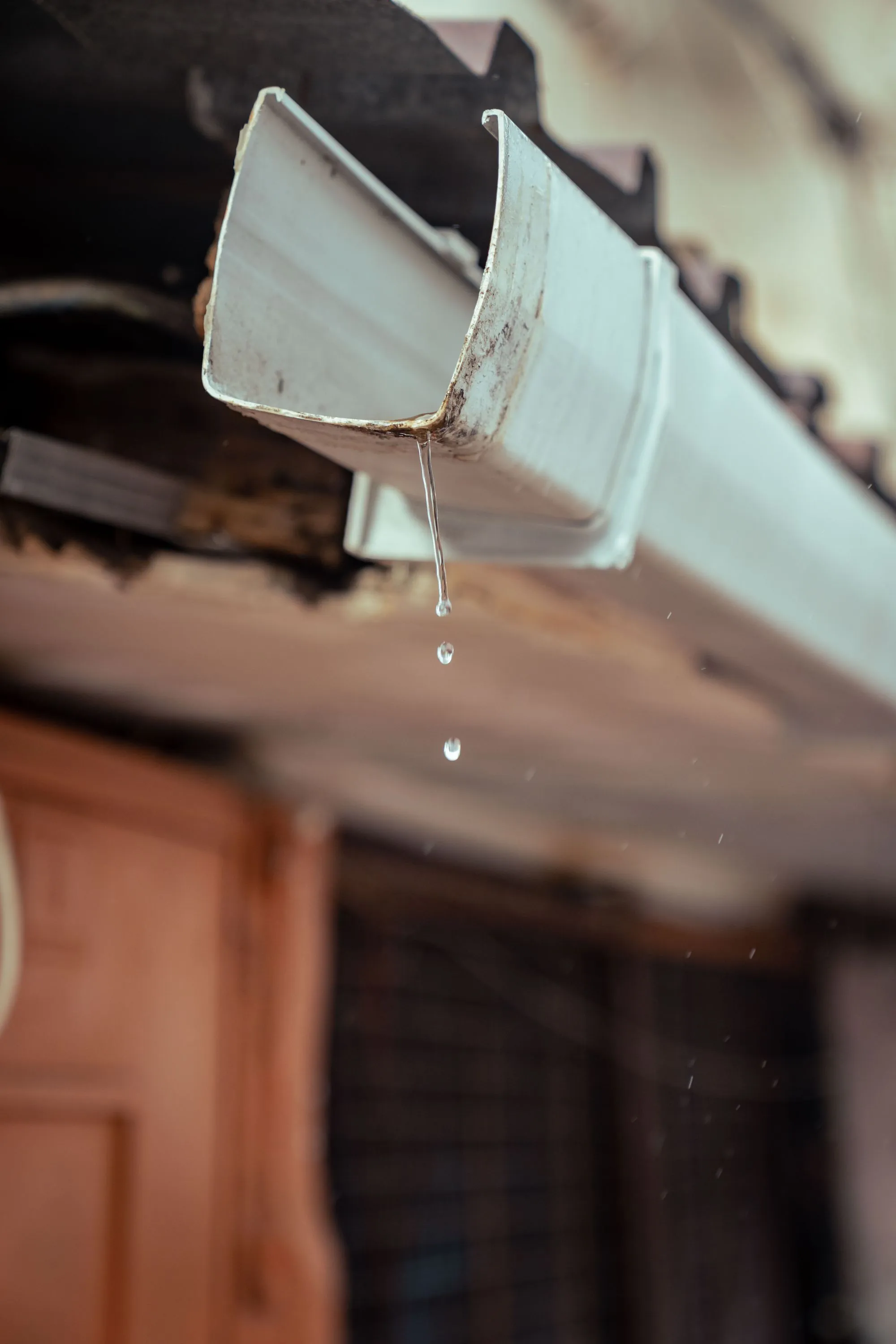 Rainwater running off the end of a gutter at the eaves of a house